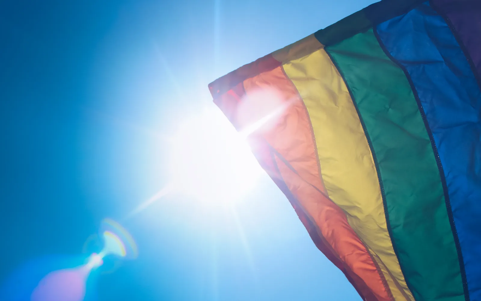 A rainbow pride flag waving in the sunlight, a symbol of LGBTQ pride and community